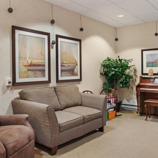 A cozy living room featuring a sofa, artwork on the walls, and a piano in the corner.