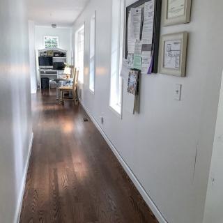 A bright hallway with wooden floors and decorated walls leading to a room.