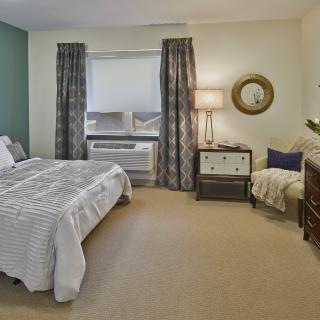A cozy bedroom with a bed, patterned curtains, and stylish decor.