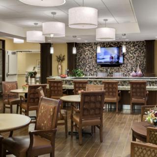 A modern dining area with stylish seating and a decorative wall, featuring soft lighting and a mounted television.