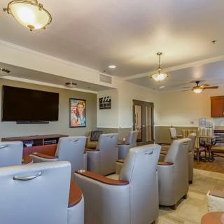 A comfortable lounge area featuring plush chairs, a large television, and modern decor.