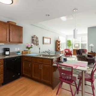 Open floor plan featuring a kitchen with wooden cabinets, dining table, and a living room with ample natural light.