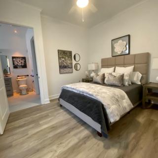 A modern bedroom featuring a stylish bed with plush pillows, elegant artwork, and wooden flooring.