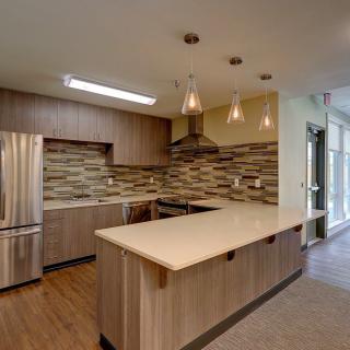 A modern kitchen with sleek wood cabinetry, a central island, and stainless steel appliances.