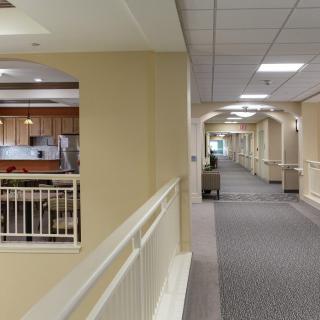 A well-lit corridor with a view of an adjacent open kitchen area.