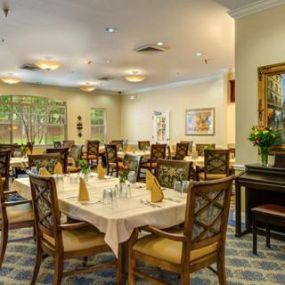 An elegant dining room with neatly arranged tables and chairs, featuring warm lighting and tasteful decor.