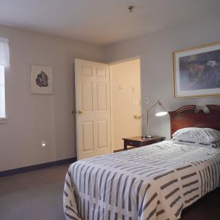 A tidy bedroom with a single bed, striped bedding, and minimalistic decor.