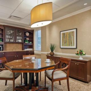 A neatly arranged conference room with a wooden table and chairs, featuring decor and a large ceiling light.