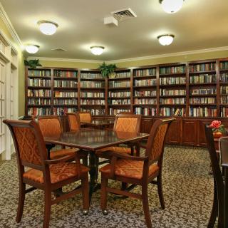 A cozy library with wooden tables and chairs surrounded by bookshelves.