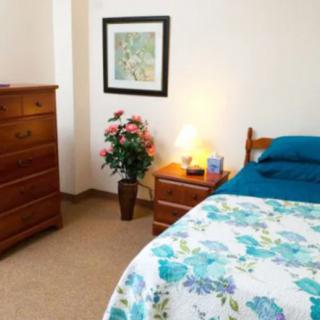 A cozy bedroom with a floral bedspread, wooden furniture, and decorative accents.