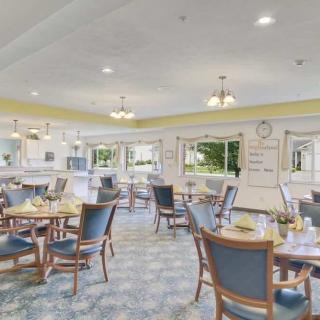 A spacious and well-lit dining room featuring neatly arranged tables and chairs, with large windows allowing natural light to fill the space.
