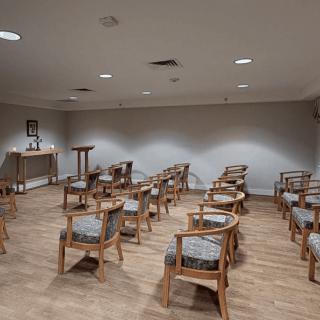 An empty conference room with rows of wooden chairs arranged neatly, ready for a meeting.