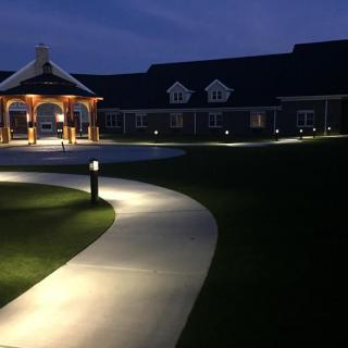 A well-lit pathway leading to a building and pavilion at night.