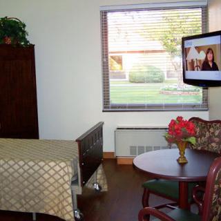 A cozy room featuring a TV, table with flowers, and a window.