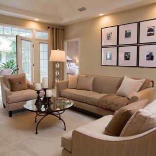 A cozy living room with beige furniture, elegant decor, and framed artwork on the wall.