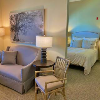 A cozy living space with a sofa and chair adjacent to a bedroom featuring a comfortable bed.