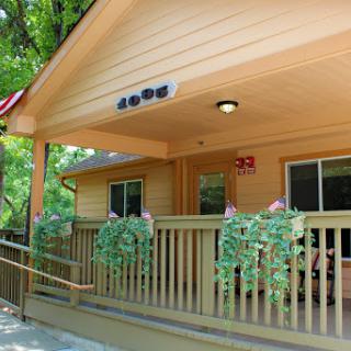 A charming wooden house with a welcoming front porch surrounded by lush greenery.
