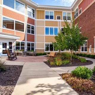 A beautifully landscaped courtyard with pathways, seating areas, and plants surrounded by a multi-story building.