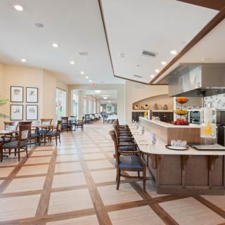 A modern restaurant interior with a spacious dining area, featuring neatly arranged tables and chairs.