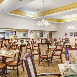 An elegant dining room featuring numerous tables and chairs adorned with chandeliers.