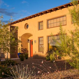 A beautifully lit house with desert landscaping and an arched doorway.