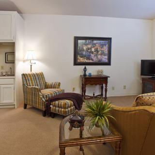 A cozy living room with comfortable seating, a table lamp, and a television.