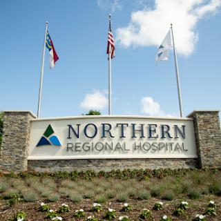 Entrance sign of Northern Regional Hospital featuring flags and landscaping.