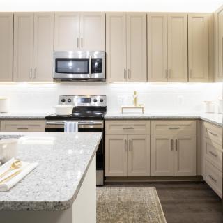 A modern kitchen featuring light wood cabinets, a granite countertop, and stainless steel appliances.