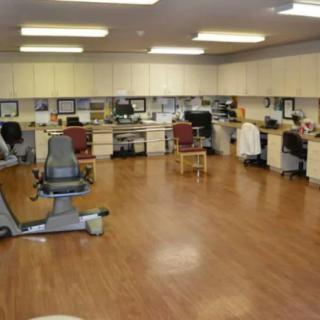 A spacious fitness room with exercise equipment and office workstations.