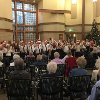 A choir performing a Christmas concert for a senior audience in a decorated indoor venue.
