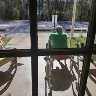 People sitting in wheelchairs enjoying the outdoor sunlight.