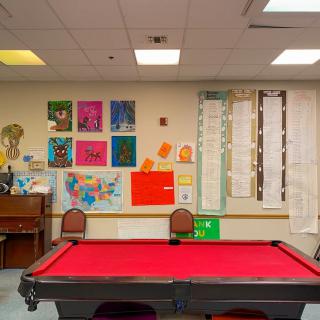 A vibrant game room featuring a red pool table and colorful artworks on the walls.