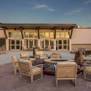 An outdoor patio area with seating around a fire pit in front of a building.