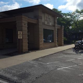 A corner view of a building with prominent architectural features and a parking area.