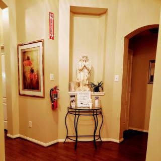 A warmly lit hallway features a decorative statue, painting, and a fire extinguisher.