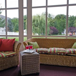 A cozy sunroom featuring wicker furniture and a scenic outdoor view.