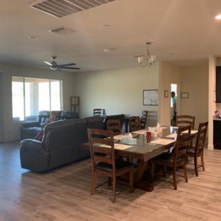A spacious open-plan living and dining area with wood flooring and comfortable furniture.
