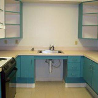 An empty kitchen with blue cabinets and a stove.