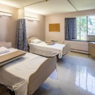 A hospital room with two beds and a window.