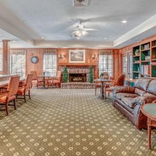 A cozy lounge area with a fireplace, comfortable seating, and bookshelves.