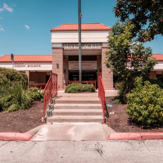 Front view of a building entrance with stairs and landscaped surroundings.