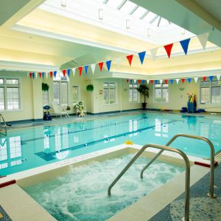 An indoor swimming and jacuzzi area with bunting flags at a leisure center.