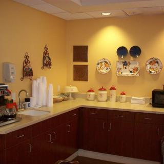A cozy break room with a kitchenette, featuring a coffee station and decorative wall plates.