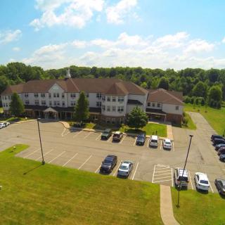 Aerial view of a building with a parking lot surrounded by trees and greenery.