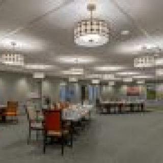 A spacious conference room with arranged tables and chairs under modern lighting.