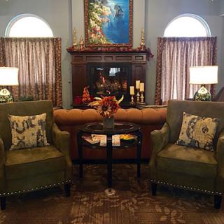 A cozy living room with two armchairs facing a decorated fireplace, complemented by warm lighting and tasteful home decor.