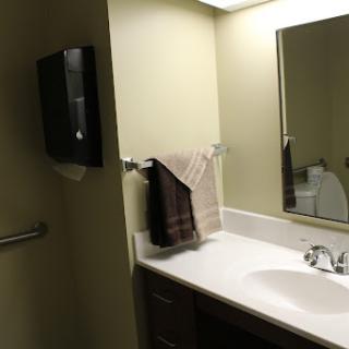A clean and well-lit bathroom featuring a sink, mirror, and neatly hung towels.