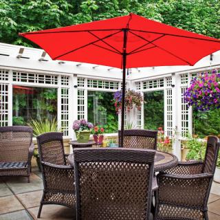 A charming outdoor patio with wicker chairs and a vibrant red umbrella.