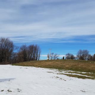 A serene winter landscape with patches of snow and a clear blue sky.