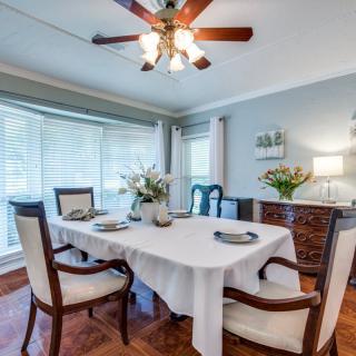 Elegant dining room with a table set for four, featuring flowers and natural light.
